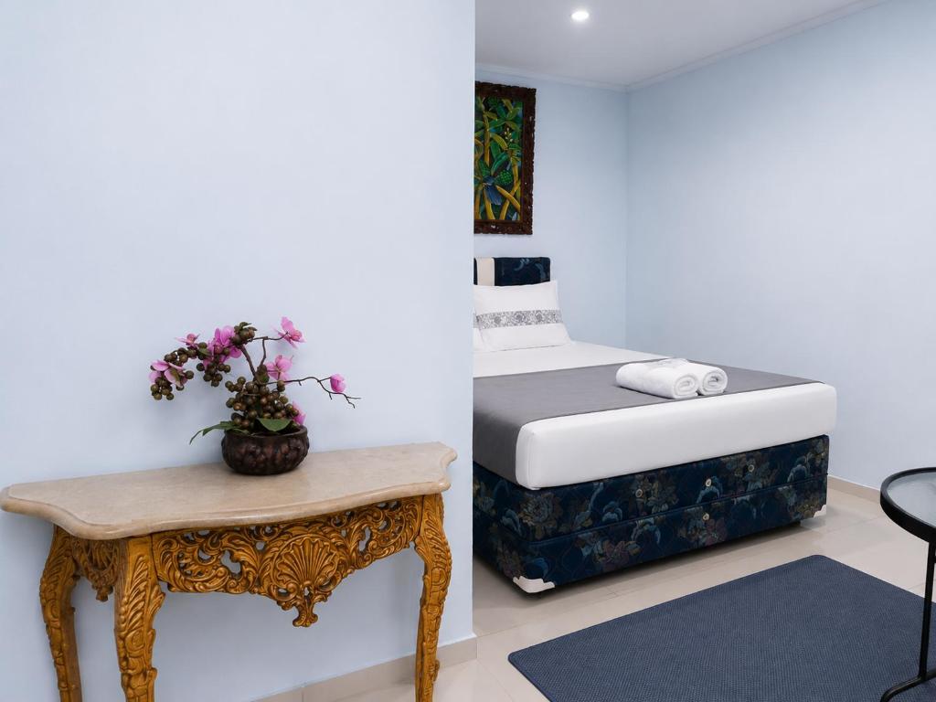 a bedroom with a bed and a table with flowers on it at NamRoom at Jatiwaringin in Jakarta