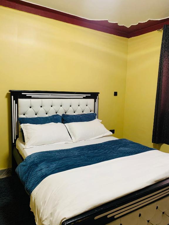 a bedroom with a large bed with blue and white pillows at Highway sunset in Namulanda