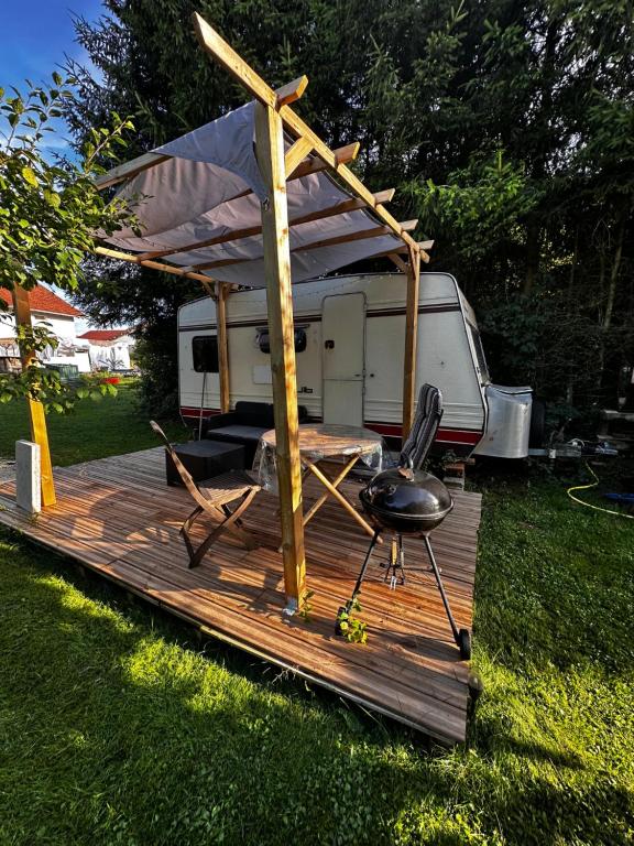 a rv with a table and a chair on a deck at La caravane du Farfadet in Flangebouche