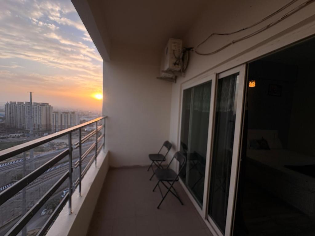 a balcony with two chairs and the sunset in the background at Skyline suites in Greater Noida