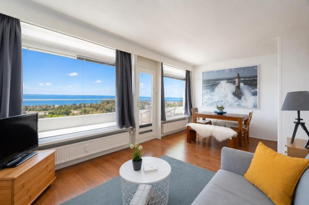 a living room with a couch and large windows at Leuchtturm-Loft mit Meerblick in Sierksdorf
