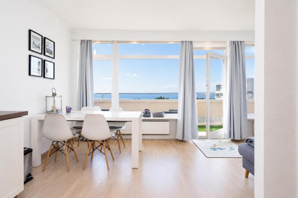 a white dining room with a table and chairs at Panoramic App A06-6 in Sierksdorf