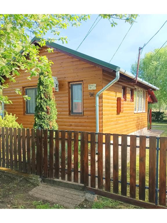 a wooden house with a fence in front of it at Fa-mìlia Vendègház in Tiszavasvári