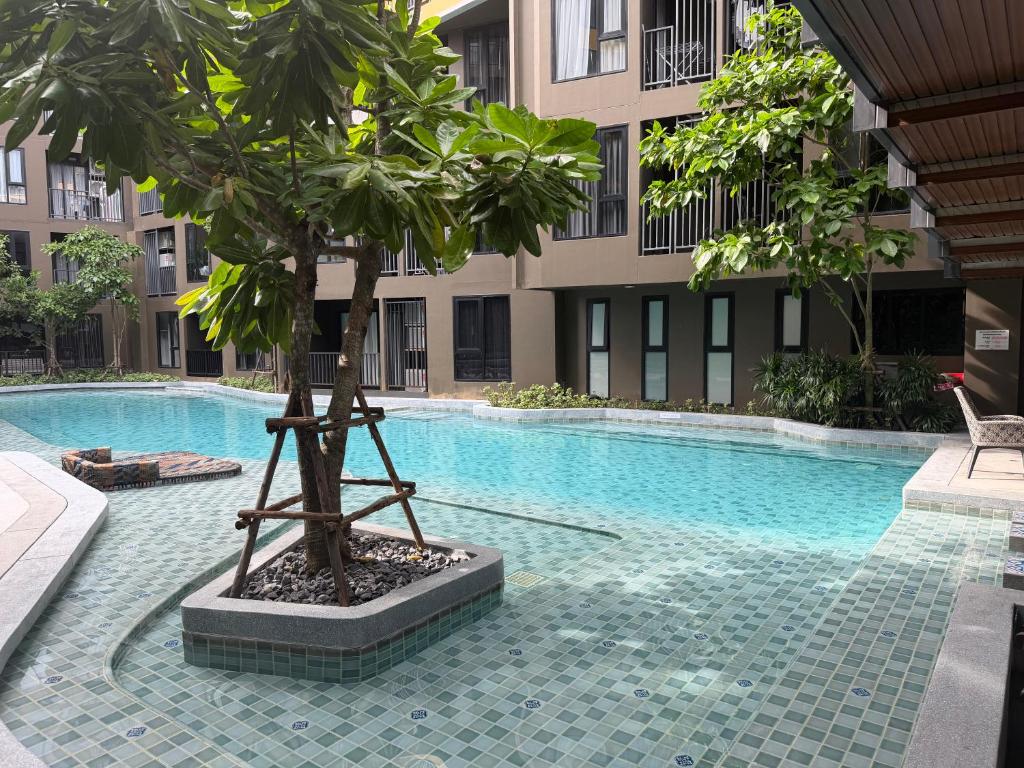 a tree next to a swimming pool in a building at A Cozy Condo Near Central-BJ in Ban Rangeng