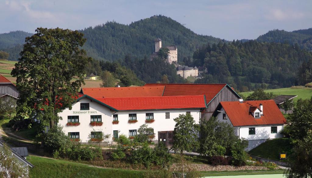 una casa blanca con techos rojos y un castillo en el fondo en Ferienhof Stanzl en Rappottenstein