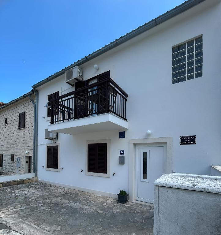 a white building with a balcony on the side at Marijana Bol Apartments in Bol