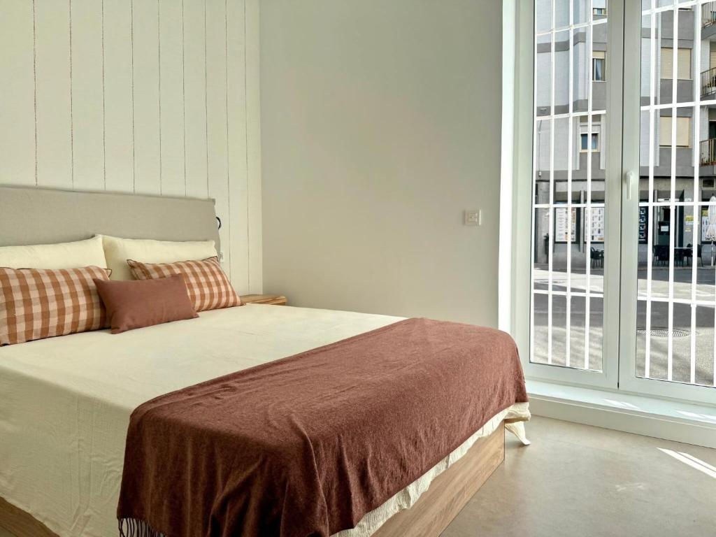 a bed in a room with a large window at Apartamento La Font in Pego