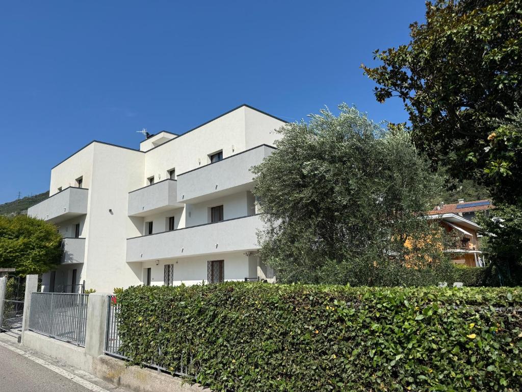 a white building with a hedge in front of it at Appartamenti Nataly in Nago-Torbole