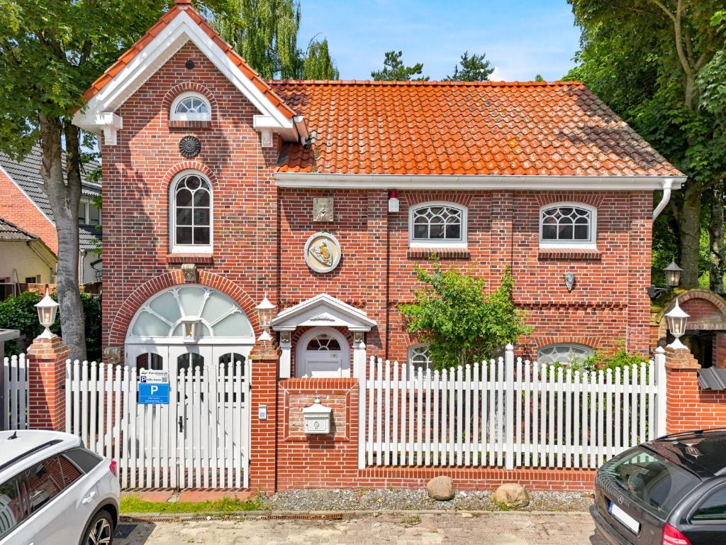 a red brick house with a white fence at Villa Aurum in Greetsiel