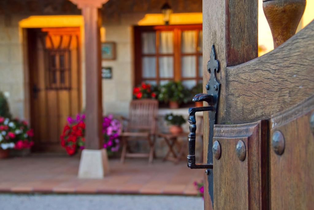 una puerta de madera abierta con un porche con flores en Posada San Pedro, en Oreña