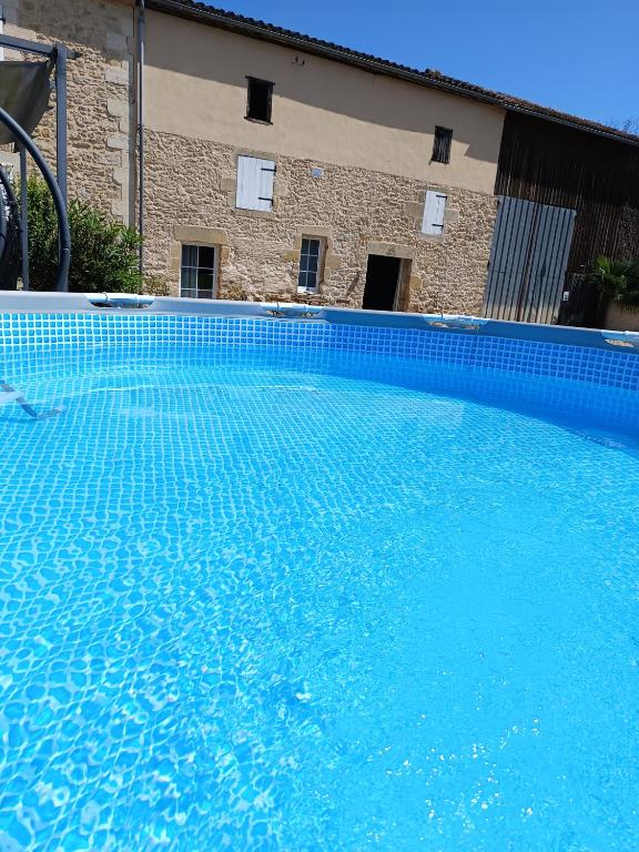 a large blue swimming pool in front of a building at L'atelier Détente et Spa in Caudrot
