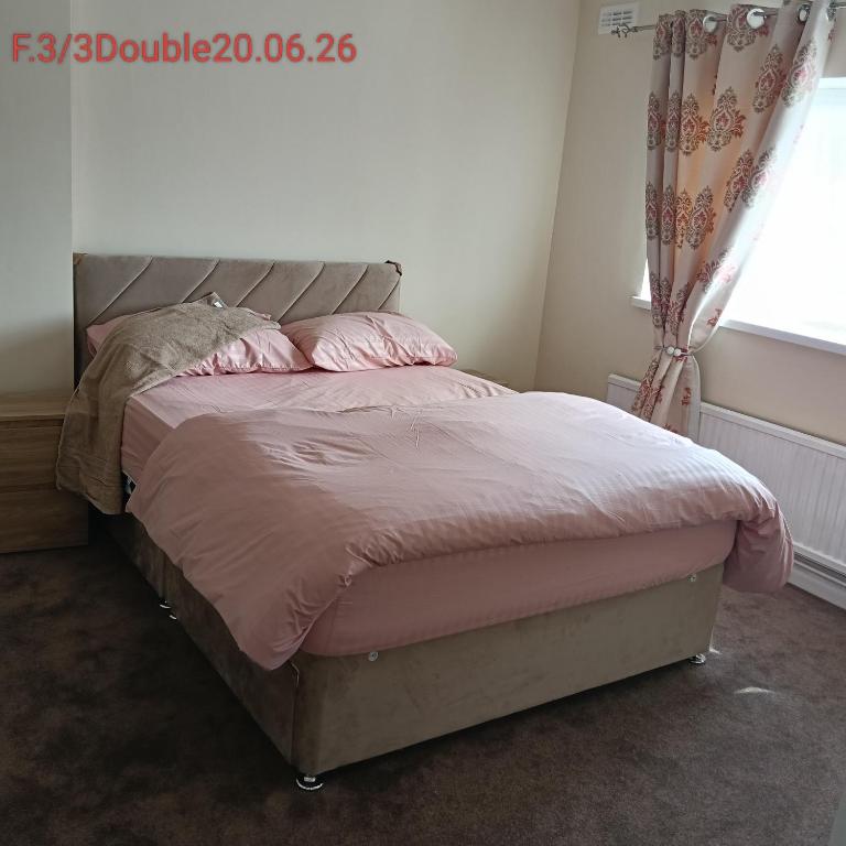 ein Bett mit rosa Laken und Kissen in einem Schlafzimmer in der Unterkunft Double bedroom with shared facilities in Lexden