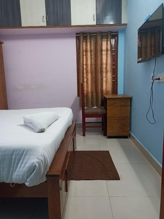a bedroom with a bed and a chair and a television at ZOLO Stays in Chennai