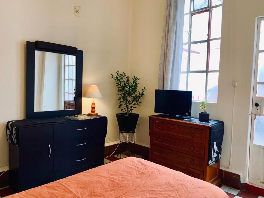 ein Schlafzimmer mit einem Bett und einer Kommode mit Spiegel in der Unterkunft Casa Luna in Mexiko-Stadt