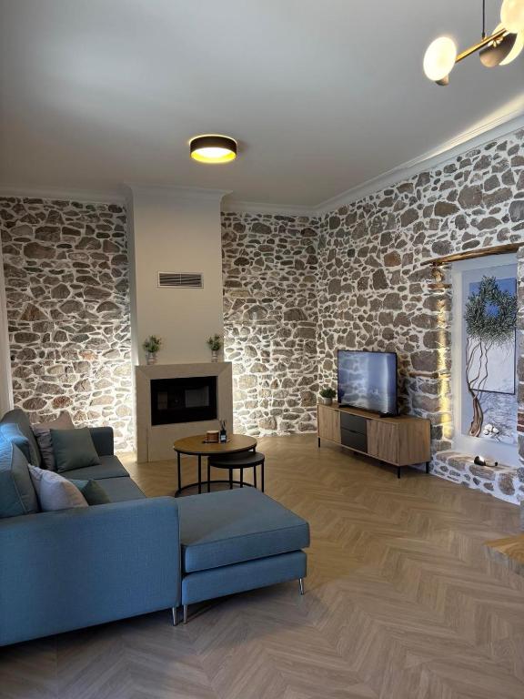 a living room with a blue couch and a stone wall at Amara Centro Luxury Apartments in Mouzaki