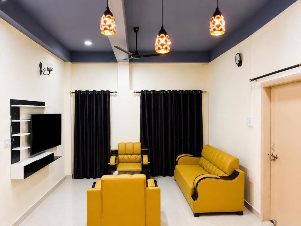 a living room with two yellow chairs and a tv at Moonleaf Stay, Guwahati in Guwahati