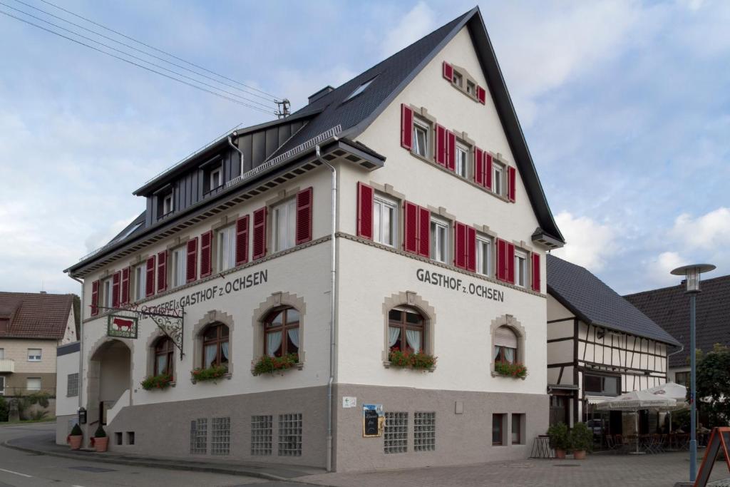 ein großes weißes Gebäude mit roten Fensterläden in der Unterkunft Gasthaus zum Ochsen in Westernhausen
