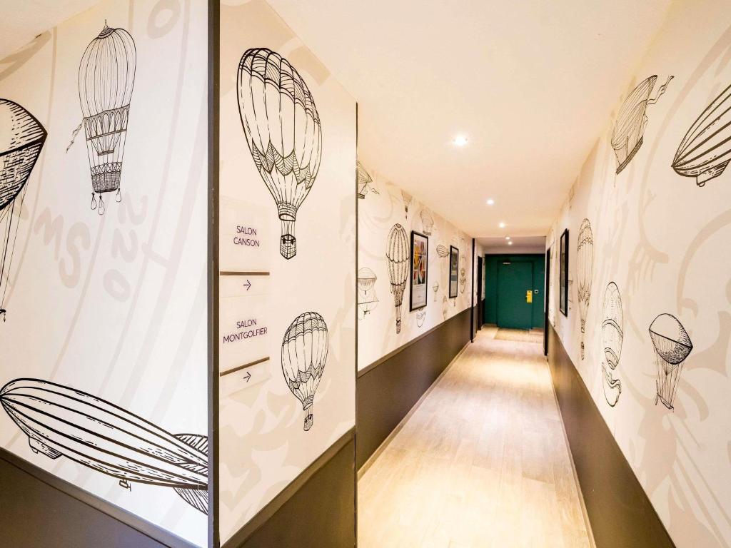 a hallway with drawings of hot air balloons on the walls at Mercure Vienne Sud Chanas in Chanas
