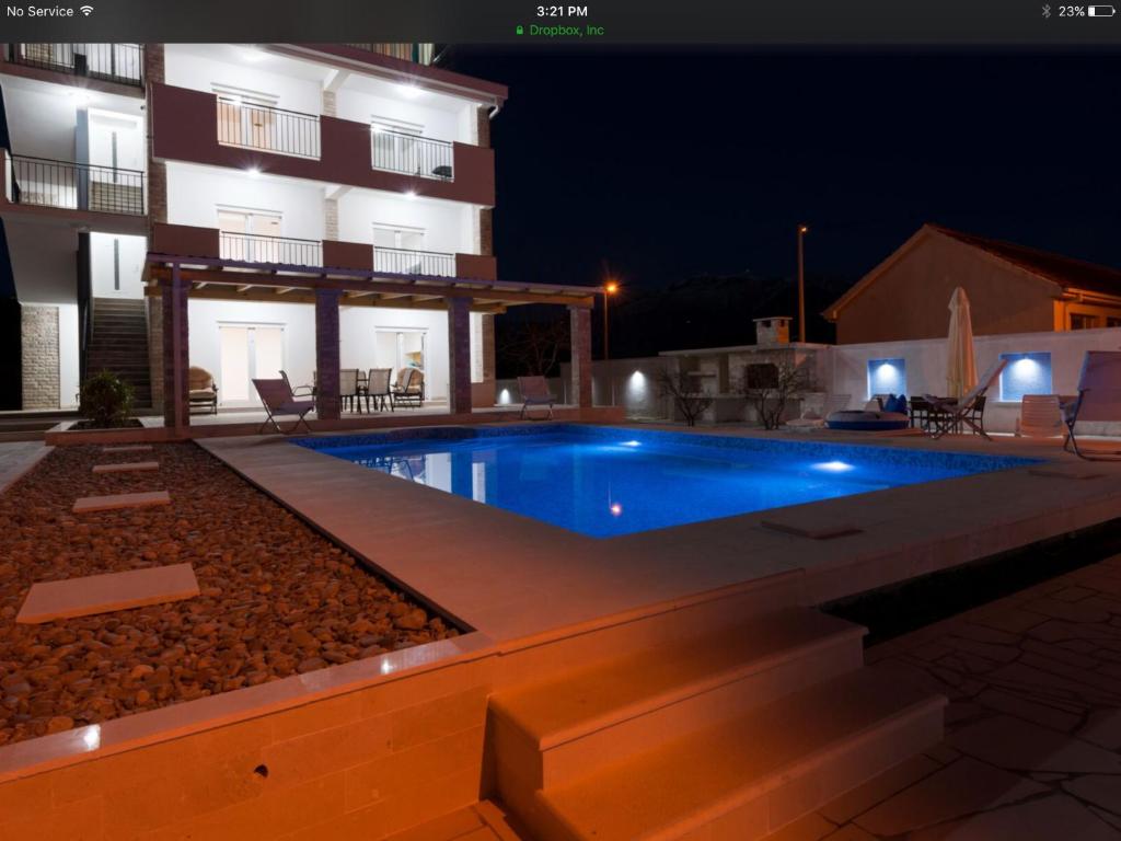 a swimming pool in front of a building at night at Villa Sandy Apartments in Tivat