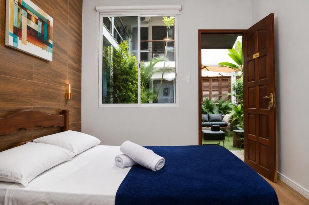 a bedroom with a bed with a blue blanket and a window at Mango Tree Ipanema in Rio de Janeiro