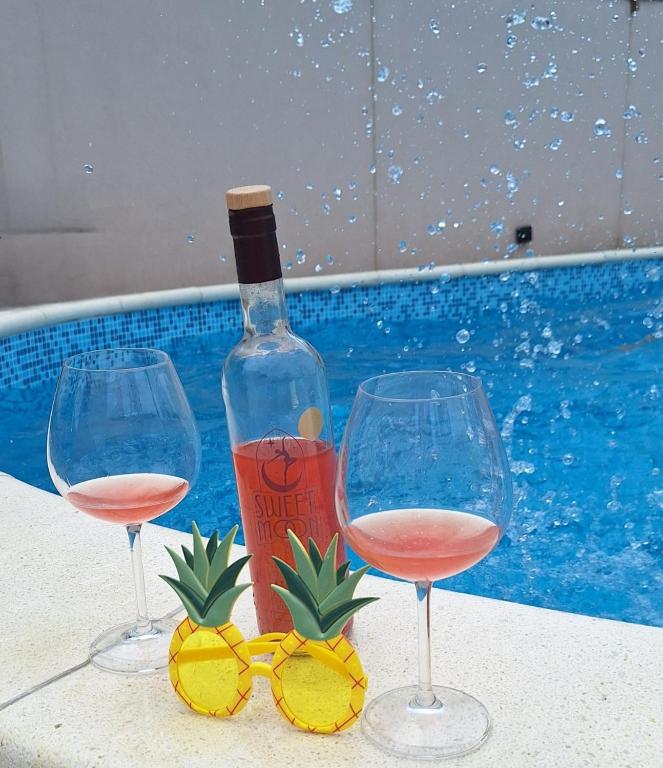 a bottle of wine and two glasses next to a swimming pool at APARTMAN BUKULJA 2 in Arandelovac