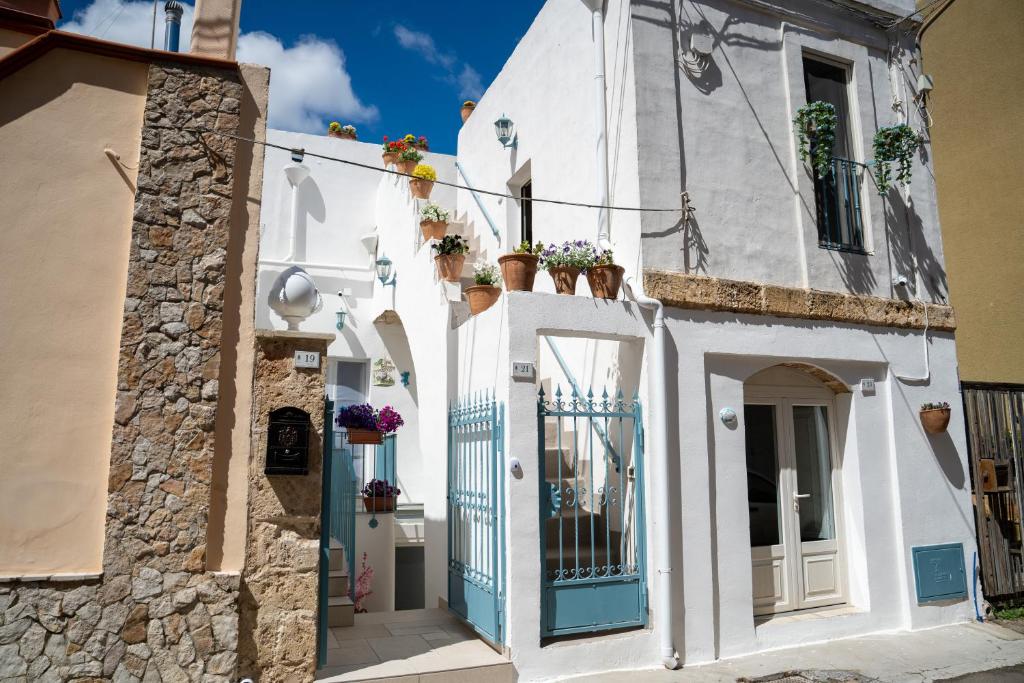 a white building with a blue door and flower pots at Ercole B&B in Ugento