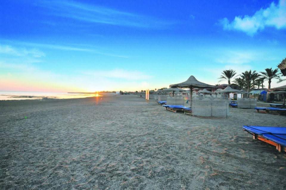 a beach with chairs and umbrellas and the ocean at OrientalCoast Marsa Alam Private Beach in Quseir