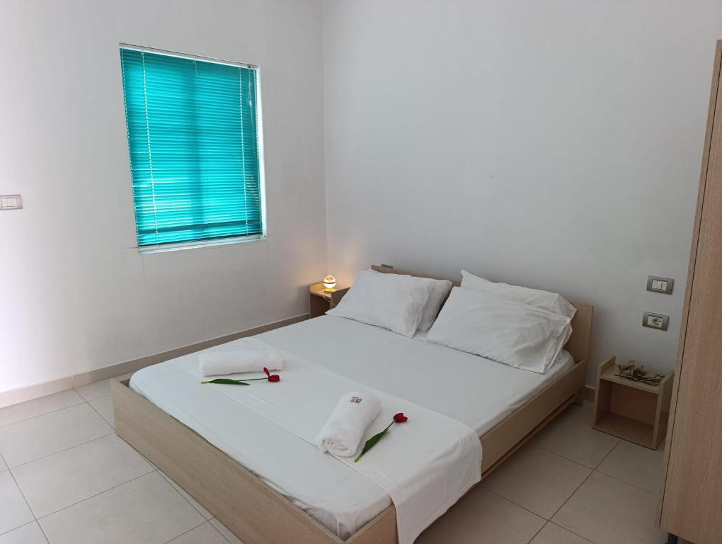 a white bedroom with a bed with two candles on it at Jasmine Apartments in Velipojë