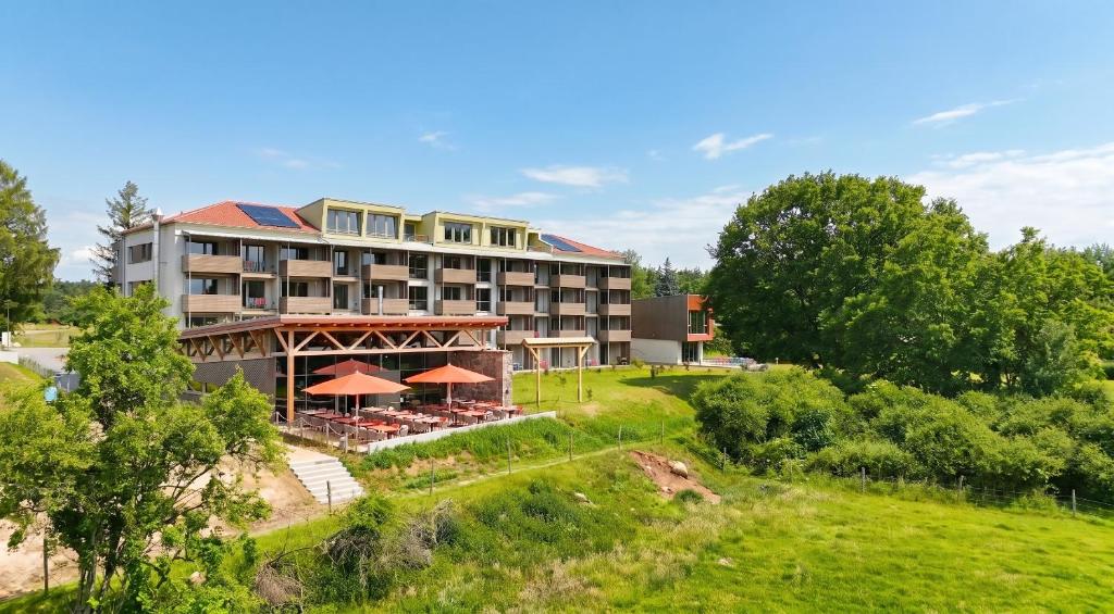 an aerial view of a resort building with tables and umbrellas at SEEZIEGE Uckermark - Ferienwohnungen am Carwitzer See in Thomsdorf