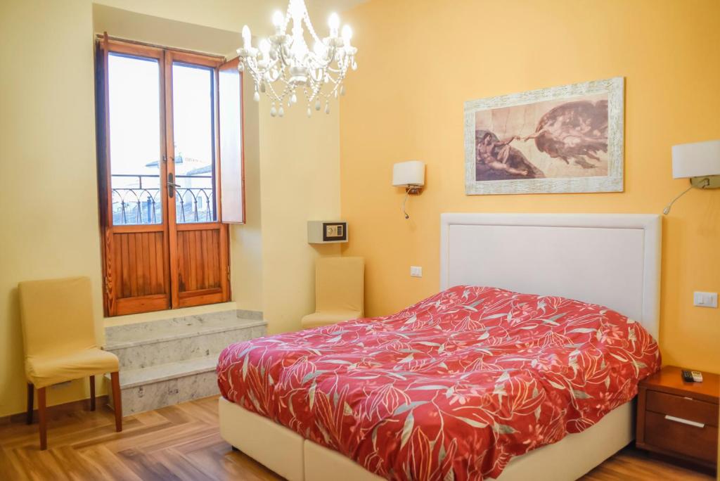 a bedroom with a bed and a window and a chandelier at Penthouse Angelo Brunetti in Rome