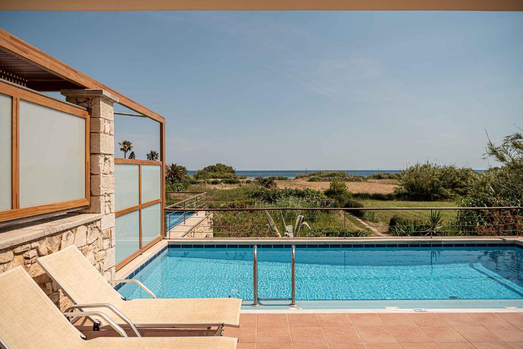 a swimming pool with two chairs next to a house at Corali Villas - Seaview, Private Pools, 450 to Beach in Kolymvari