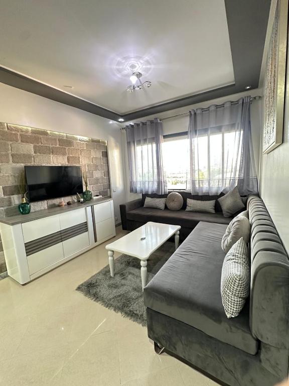 a living room with a couch and a tv at JULYA appartement centre in Tangier