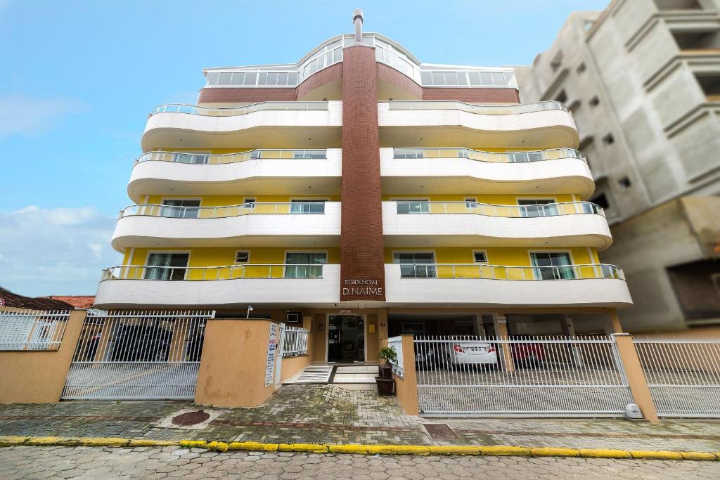 a tall apartment building with a fence in front of it at Residencial Dona Naime in Bombinhas