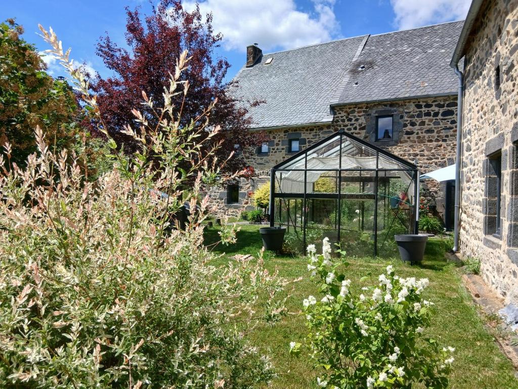 an old stone house with a glass greenhouse in the yard at Le Coudi in Saint-Pierre-le-Chastel