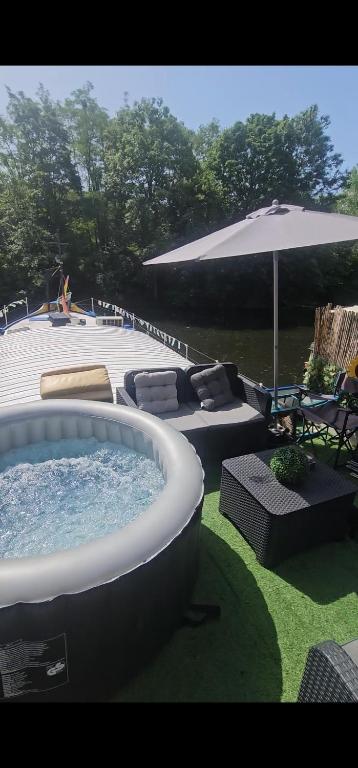 a large hot tub sitting in a yard with an umbrella at Peniche refuge Seine in Vigneux-sur-Seine