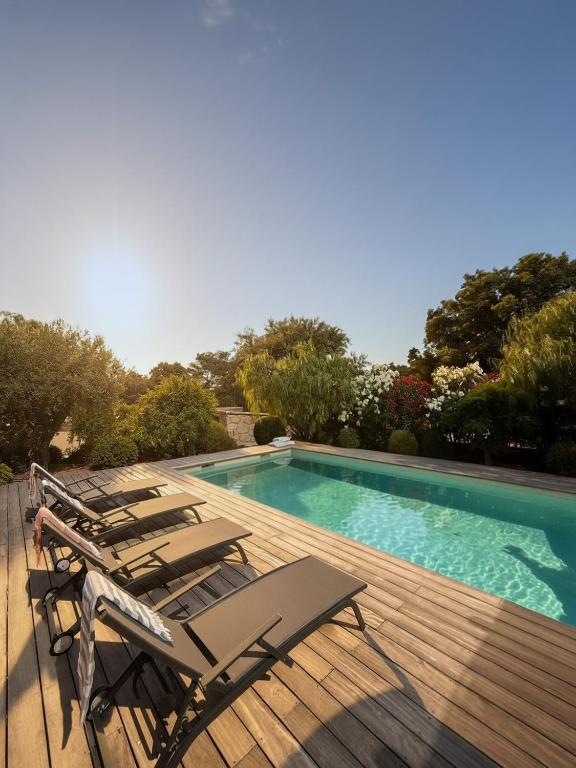 a group of chairs sitting on a deck next to a swimming pool at Villa Sébastien by Intendance Excellency in Zonza