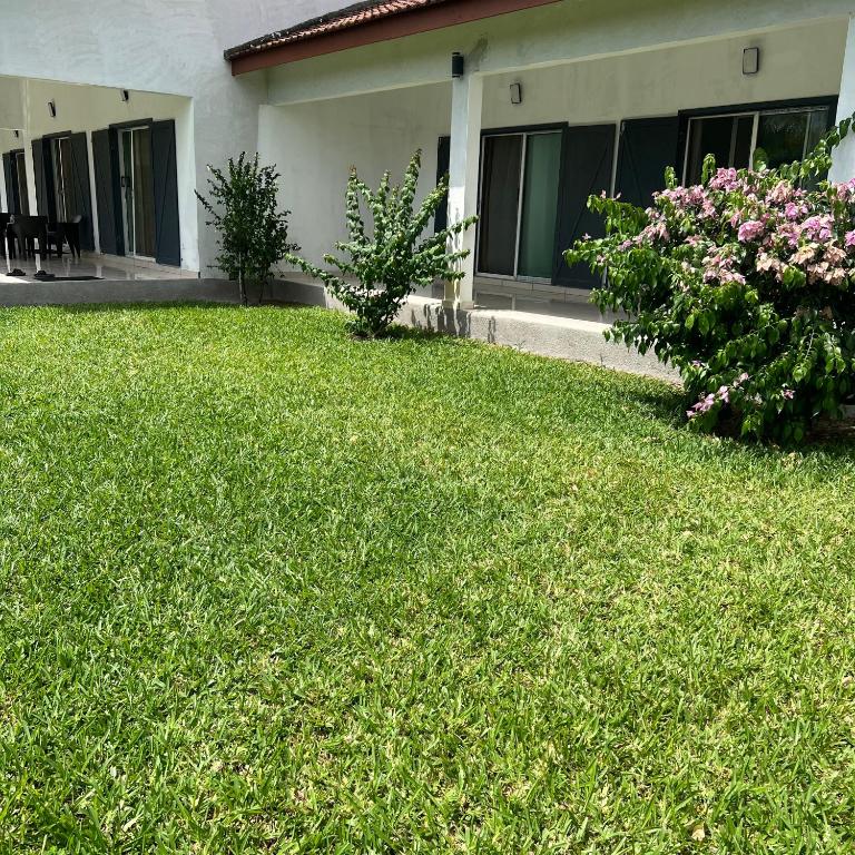 a yard of a house with green grass and flowers at La Villa Fleur d'Edene in Abidjan