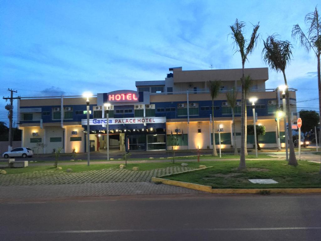 um edifício de hotel com uma palmeira em frente em Garcia Palace Hotel em Sinop