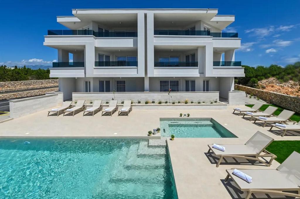 a large building with a swimming pool and chairs at Villa Gaj 2 in Novalja
