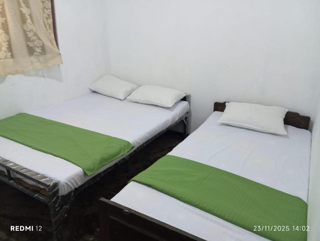 two beds in a room with green and white at Nimansala Eco Resort in Parakaduwa