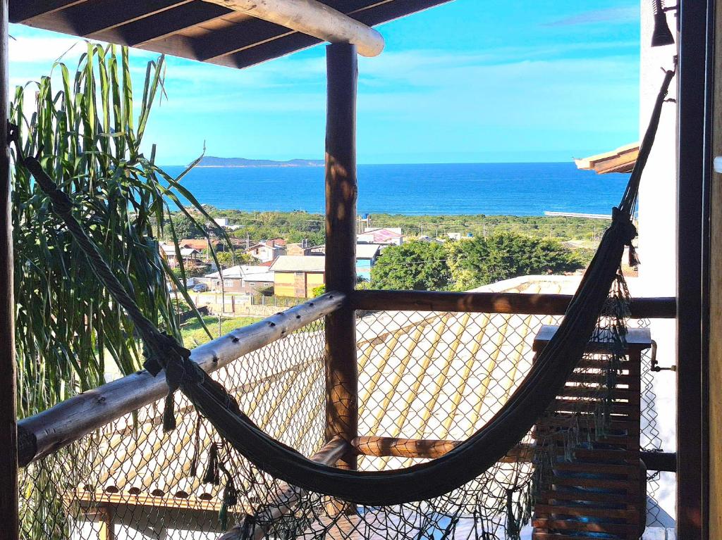 a hammock on a balcony with a view of the ocean at Residencial Hibiscos - Vista Mar in Garopaba