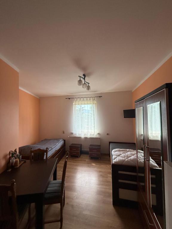 a room with two beds and a table and a window at Kuźnia Międzylesie in Międzylesie