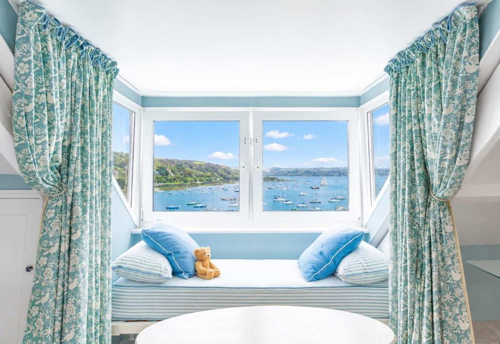 a window seat with a teddy bear sitting in front of a window at Chy En Glas - By Rowes Retreats in Falmouth
