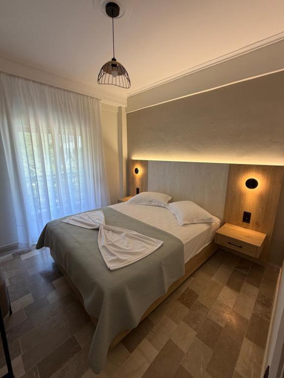 a bedroom with a large bed and a large window at Hotel Angela in Asprovalta