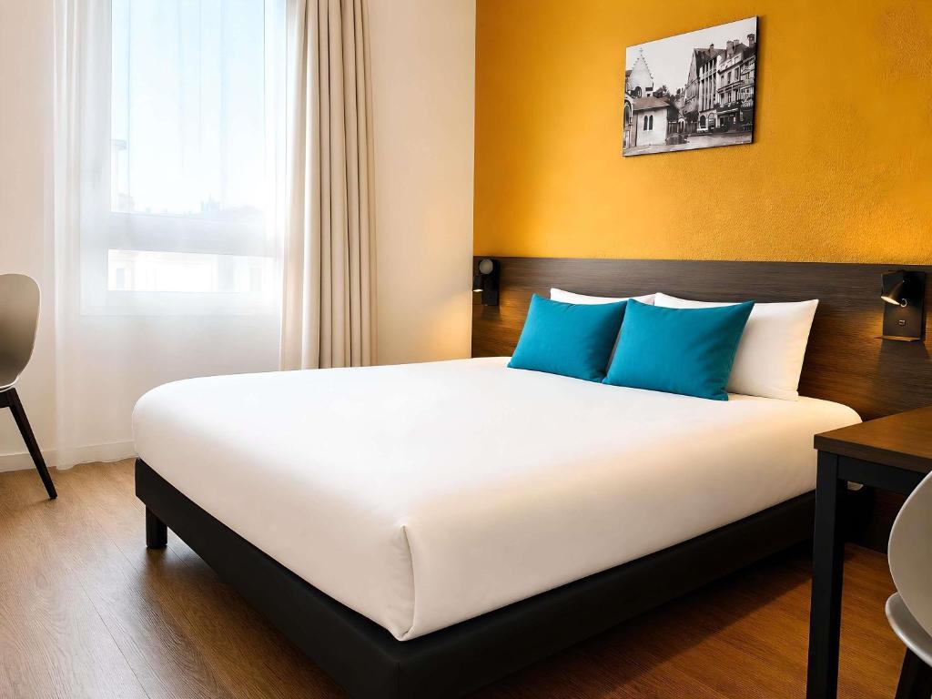 a bedroom with a large bed with blue pillows at Aparthotel Adagio Access Poitiers in Poitiers