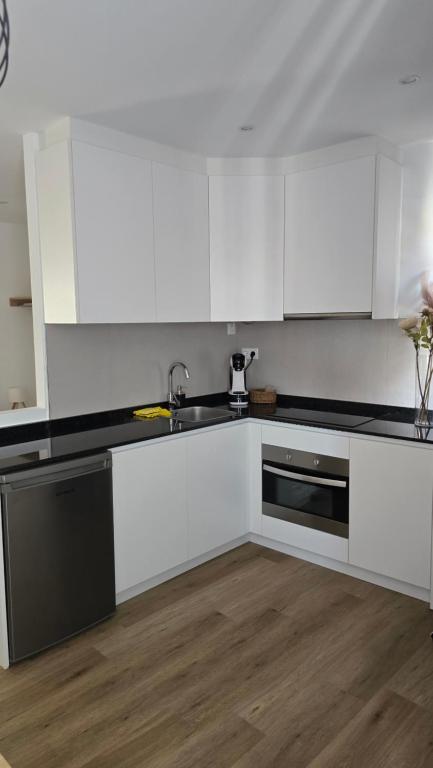 a kitchen with white cabinets and a sink at Loft Casco Viejo 4 in Ourense