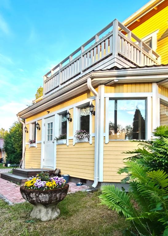 a yellow house with a porch and a flower pot at Inka's Guesthouse in Alavus