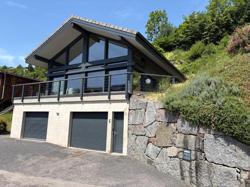 a house with two garage doors and a stone wall at Chalet du paradis in La Bresse