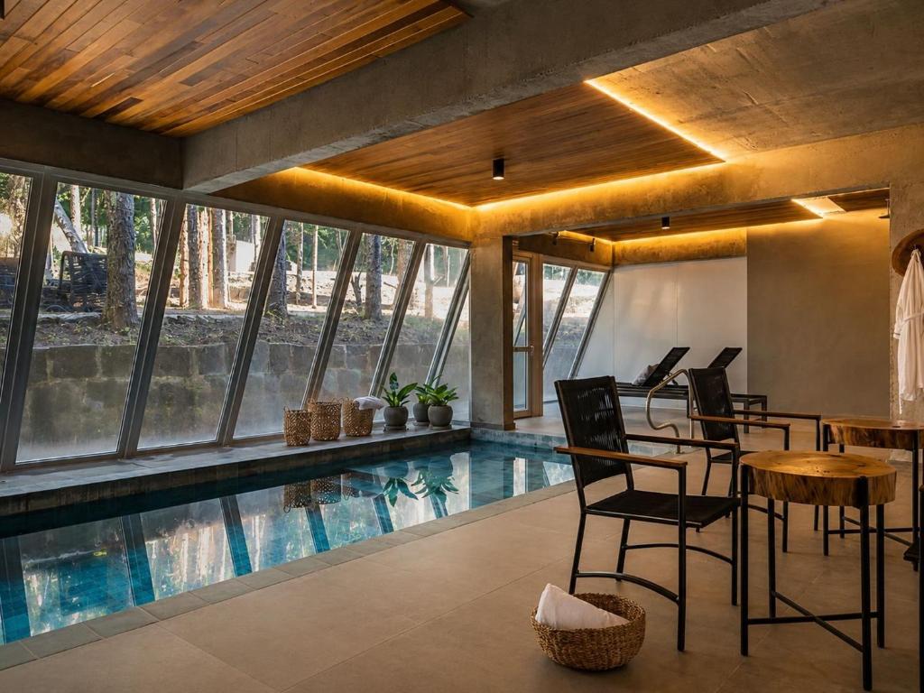 a house with a swimming pool with chairs and a table at Refúgio Boutique com Piscina Aquecida in Canela
