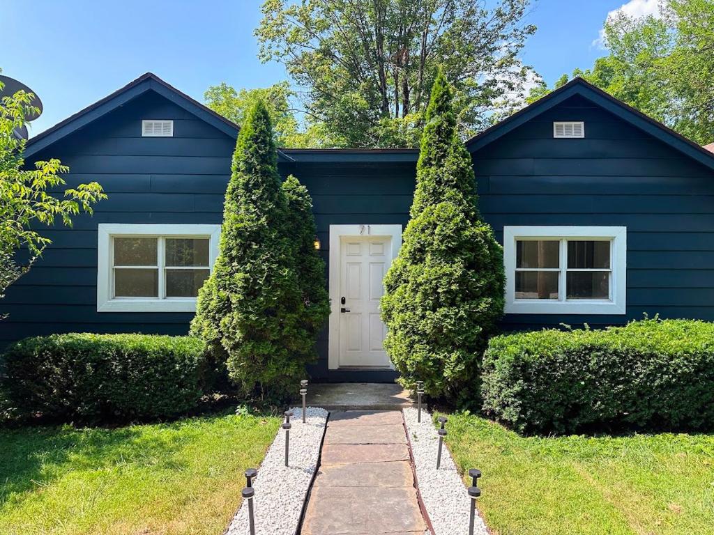 a blue house with a white door and some bushes at Cozy Catskill Escape in Catskill